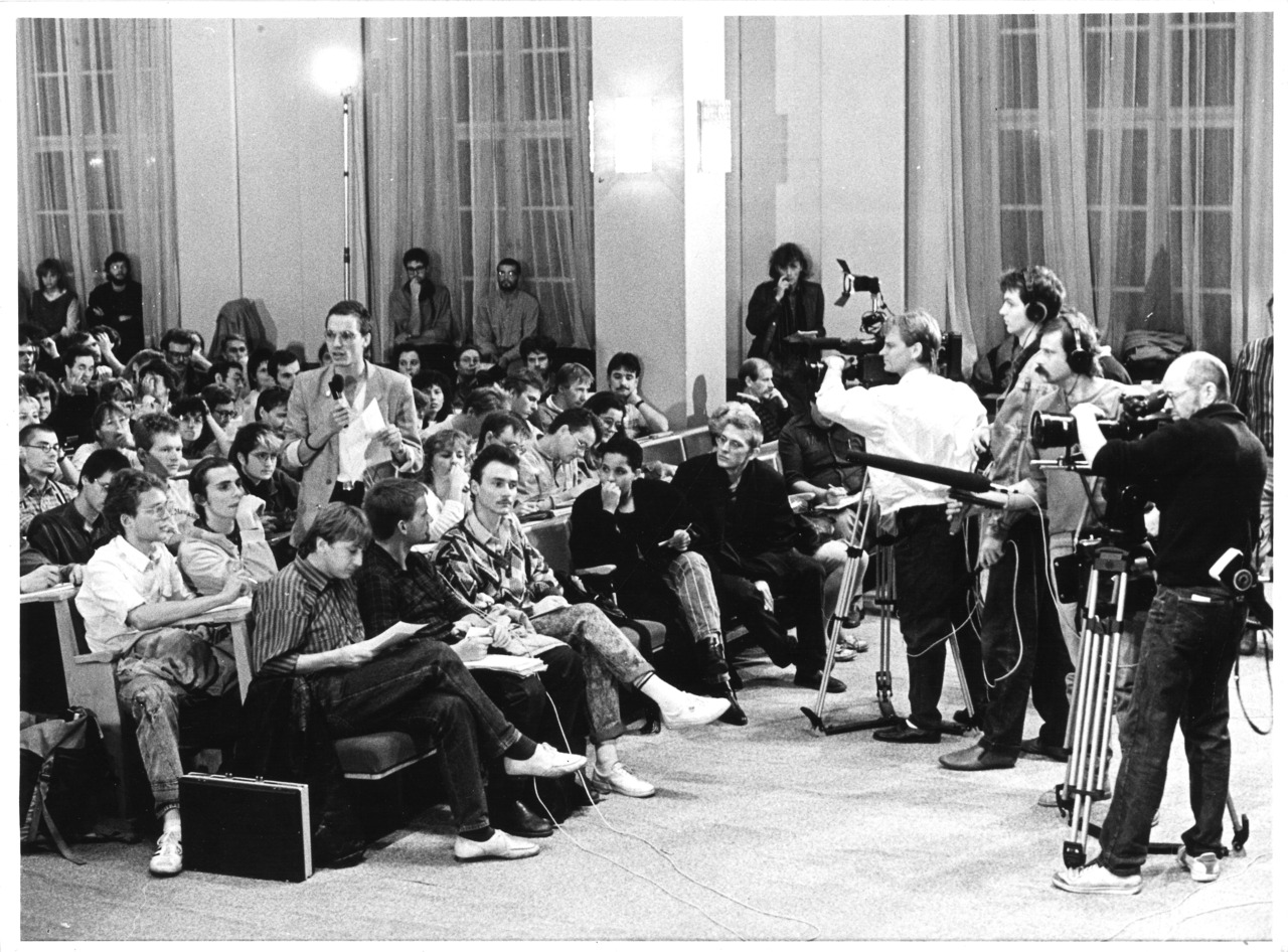 black and white foto of students discussion with cameras and microphones recording them